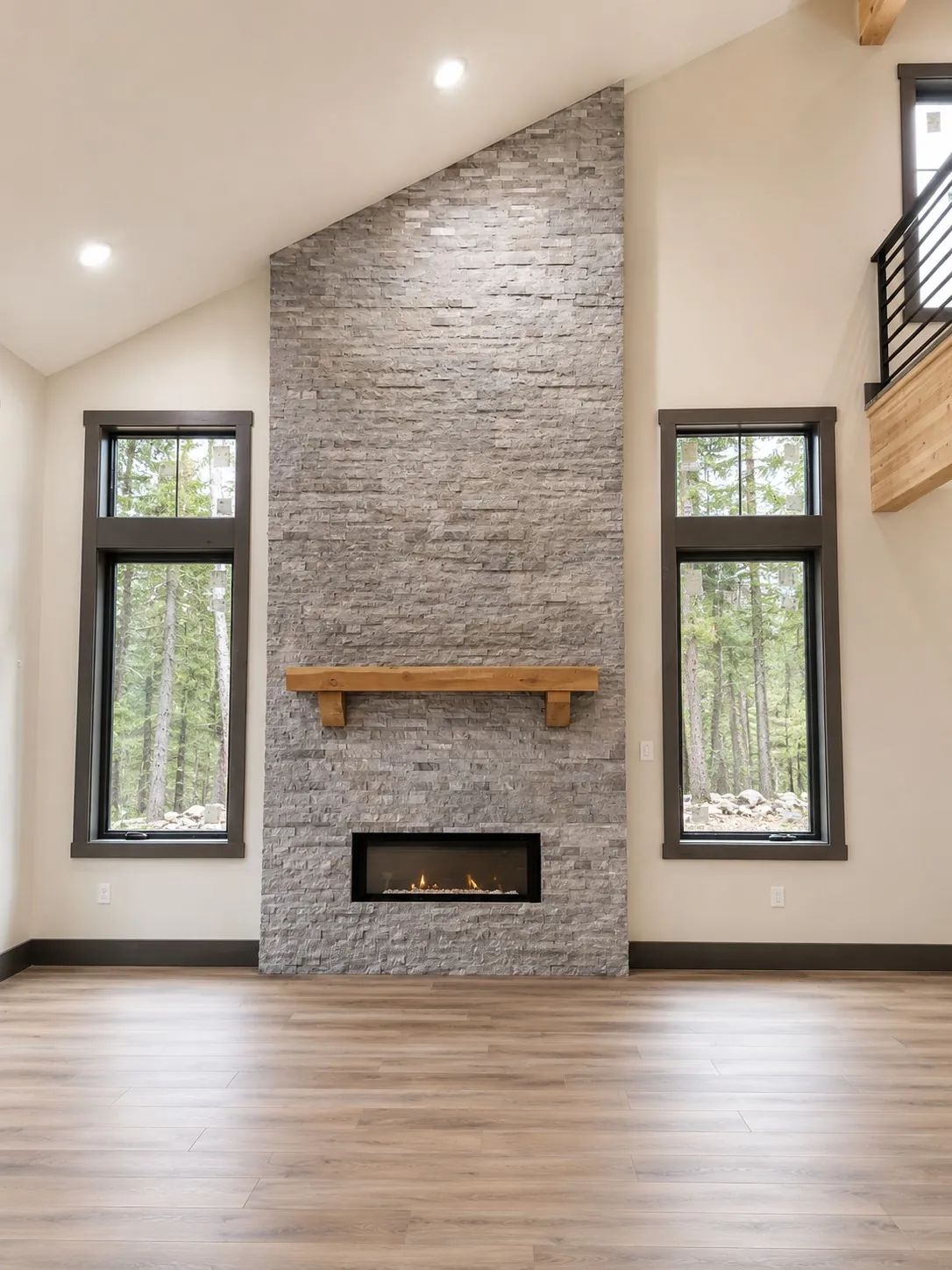 Remodeled living room with stone fireplace and tall windows